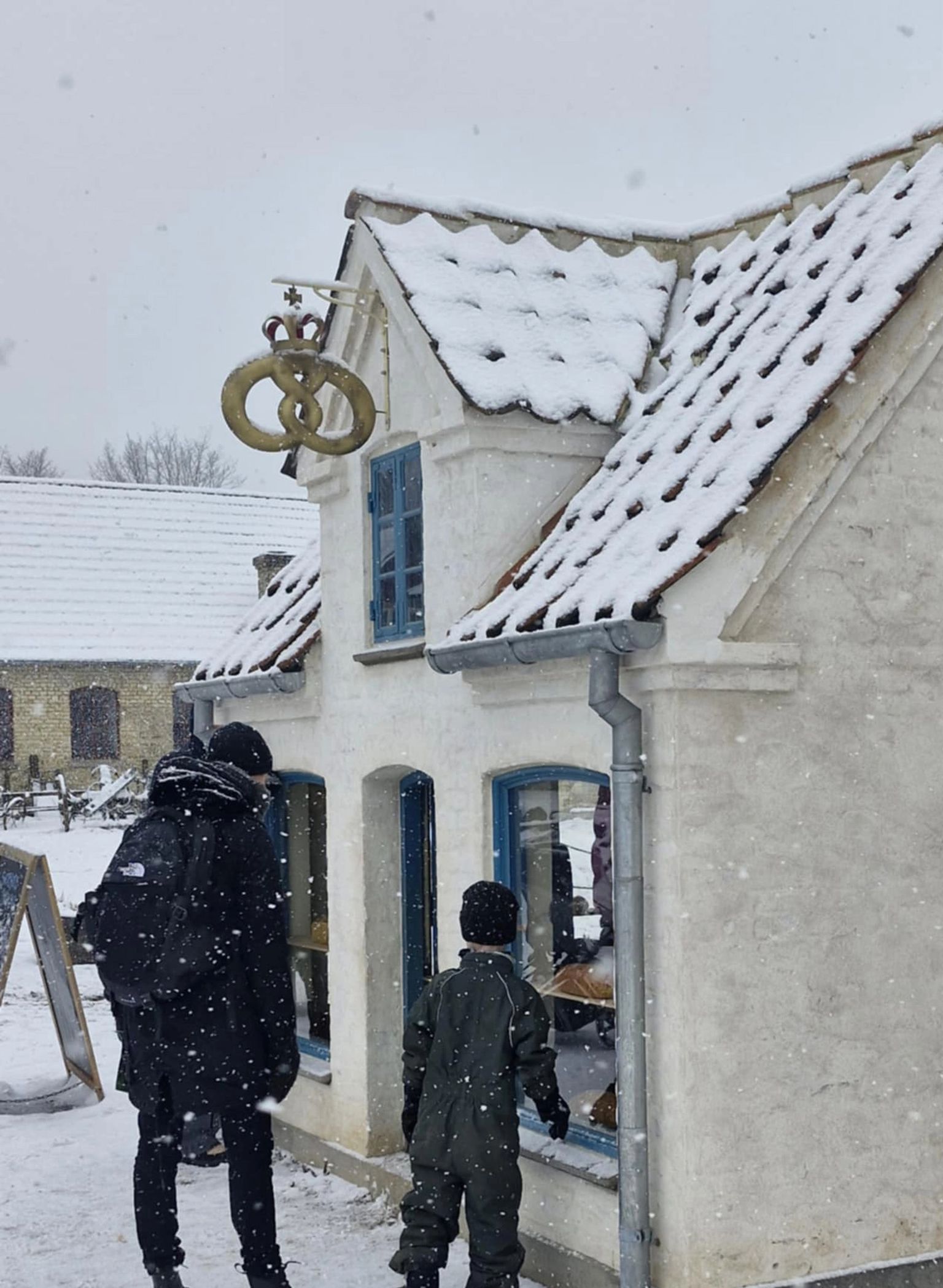Adult and child looking into the bakery building in snowy weather