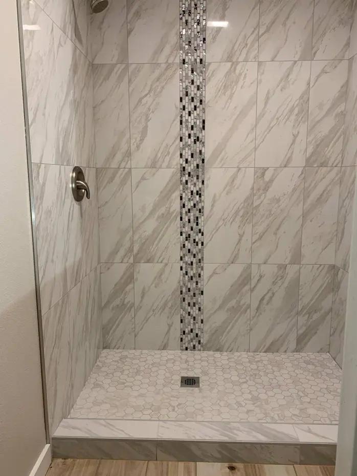 Bathroom renovation with marble vanity and pebble accent wall