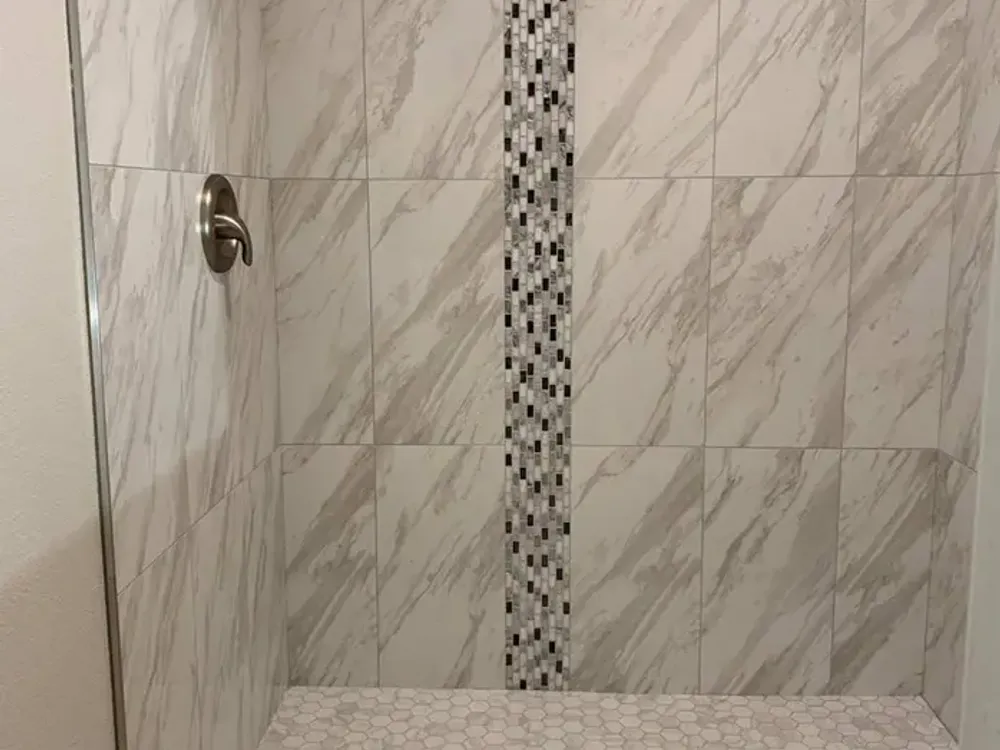 Bathroom renovation with marble vanity and pebble accent wall