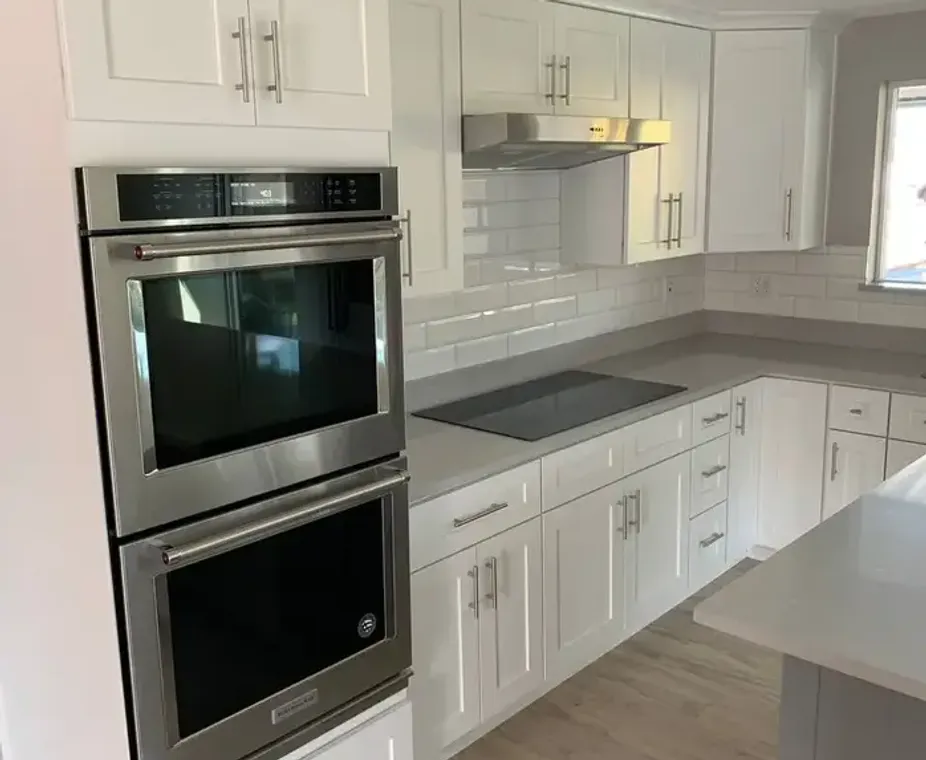 White kitchen cabinets with double oven and subway tile backsplash