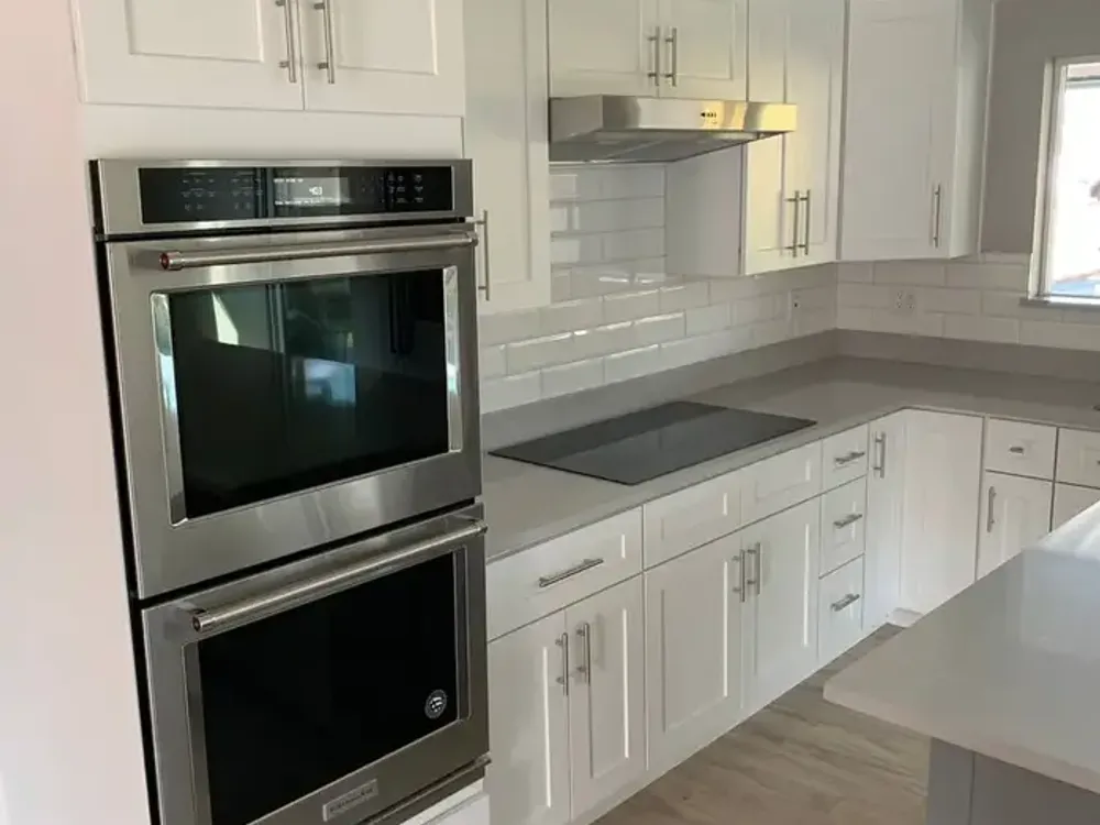 White kitchen cabinets with double oven and subway tile backsplash