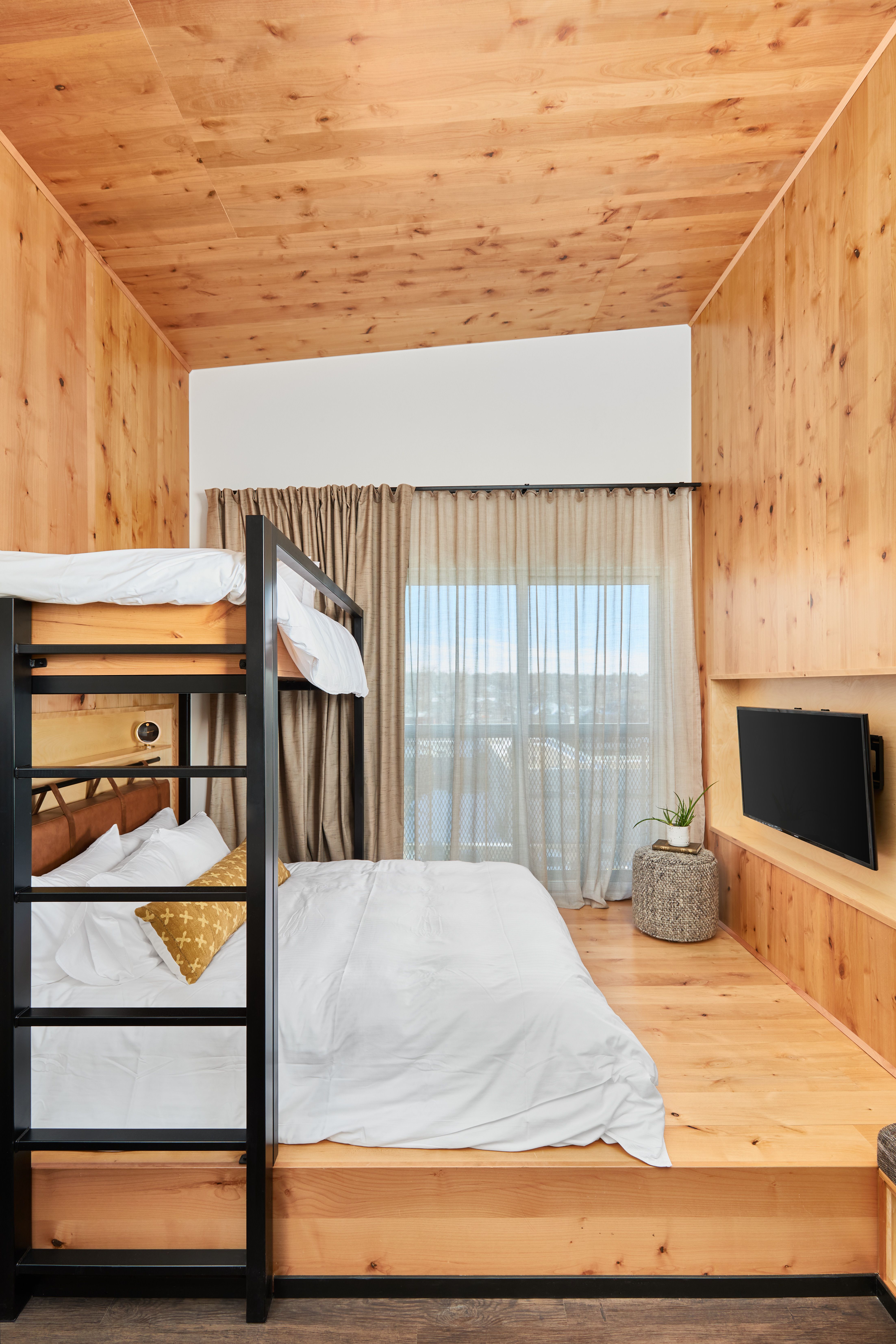 A room with a bunk bed, TV, and window