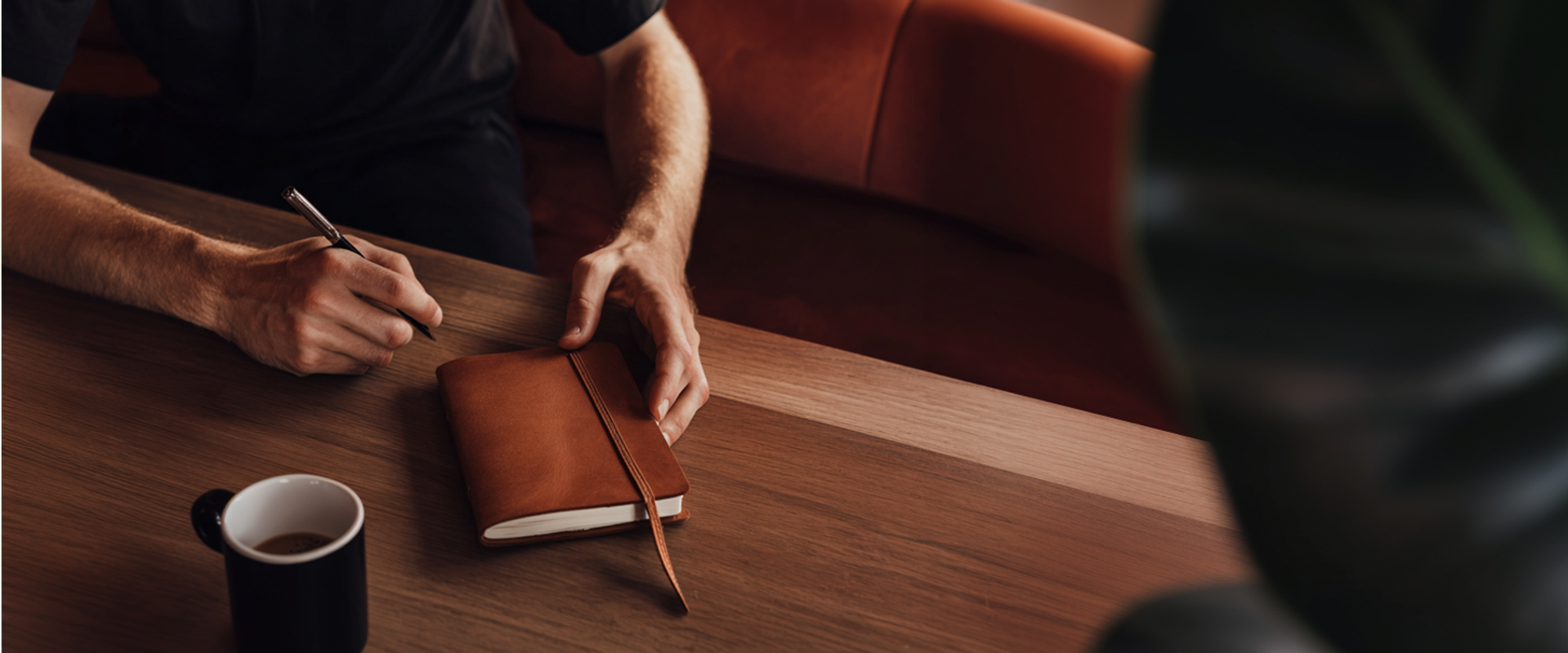 Person in a coffee shop writing on a journal