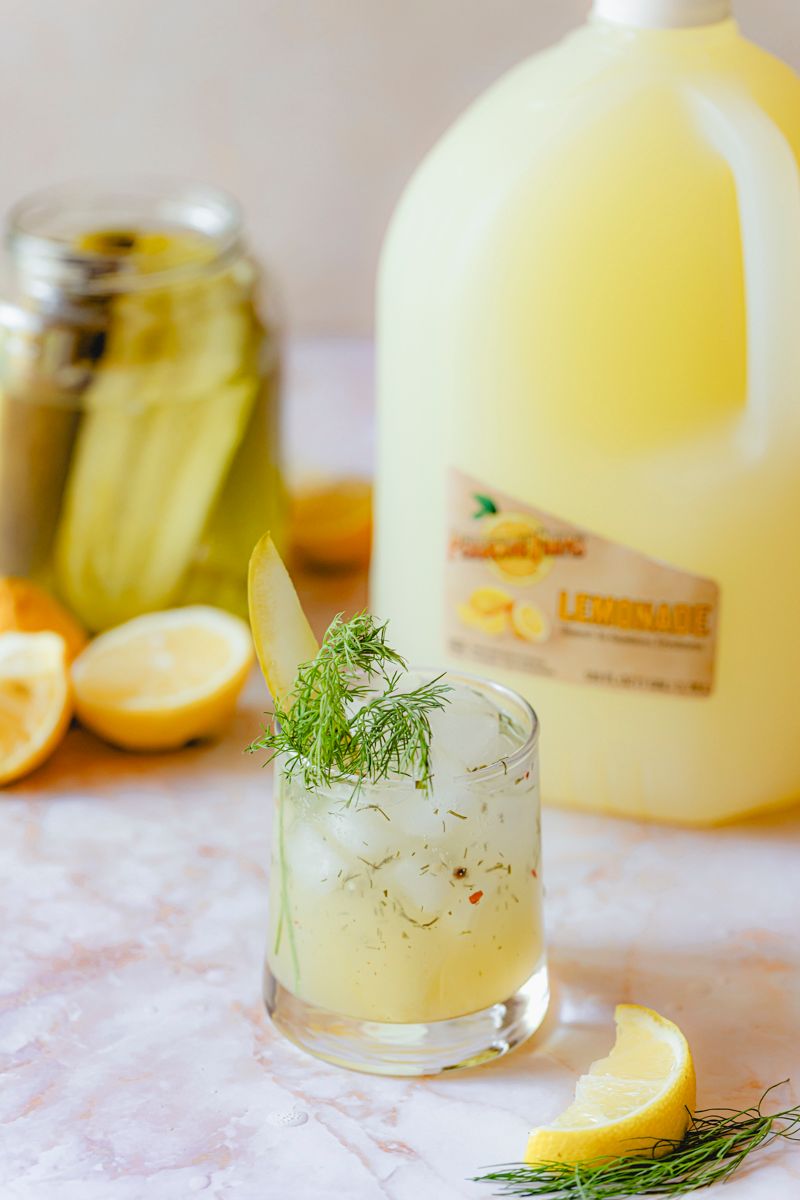 Sparkling Pickle Lemonade made with Perricone Farms Lemonade and pickle brine, served over ice with fresh dill and a pickle spear