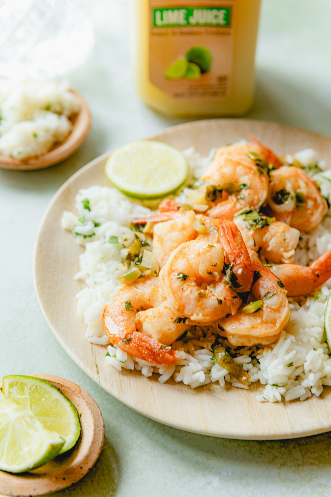 Lime Marinated Shrimp served over rice and topped with salsa verde made with Perricone Farms Lime Juice, surrounded by fresh herbs, lime wedges, and a bottle of juice