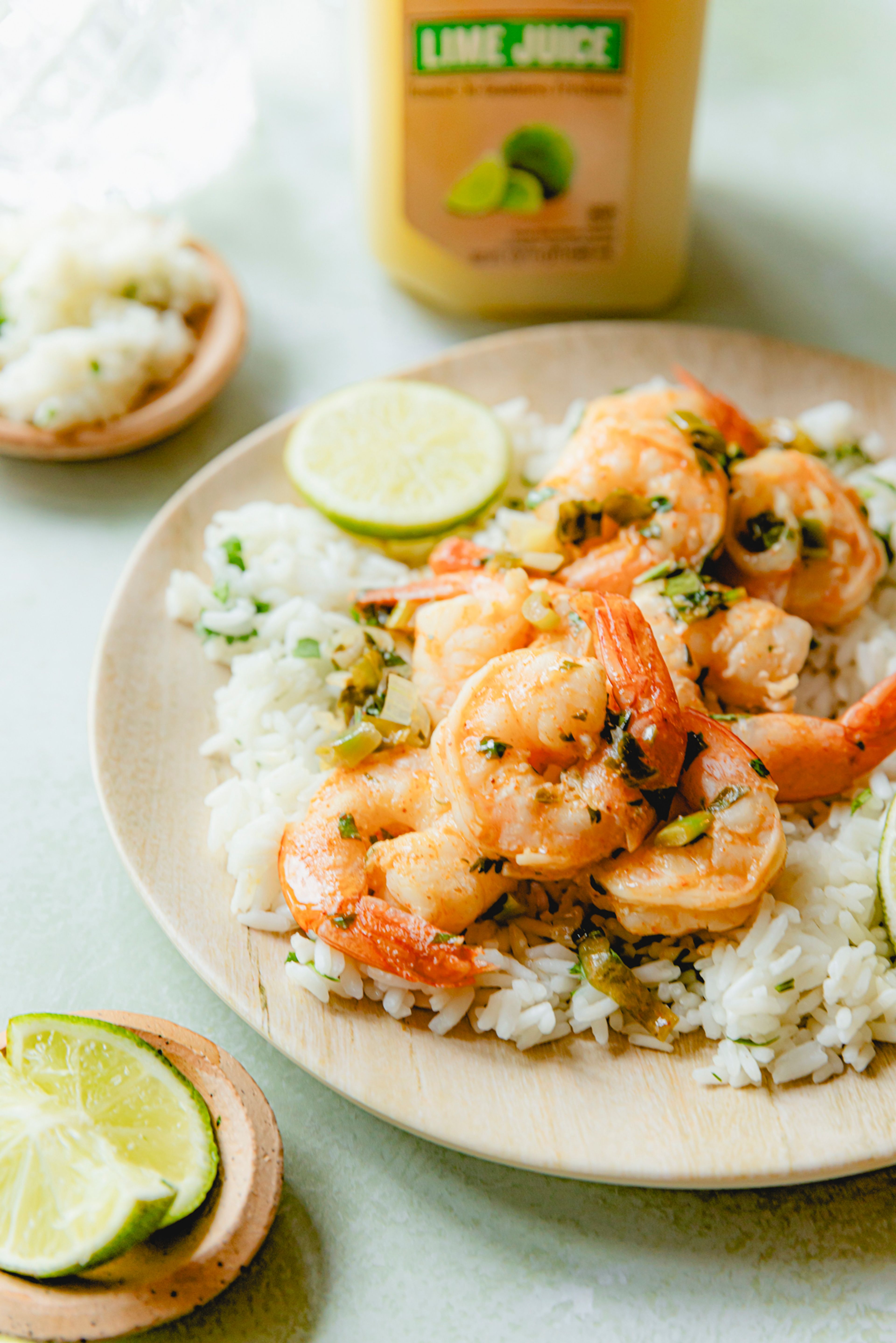 Lime Marinated Shrimp served over rice and topped with salsa verde made with Perricone Farms Lime Juice, surrounded by fresh herbs, lime wedges, and a bottle of juice