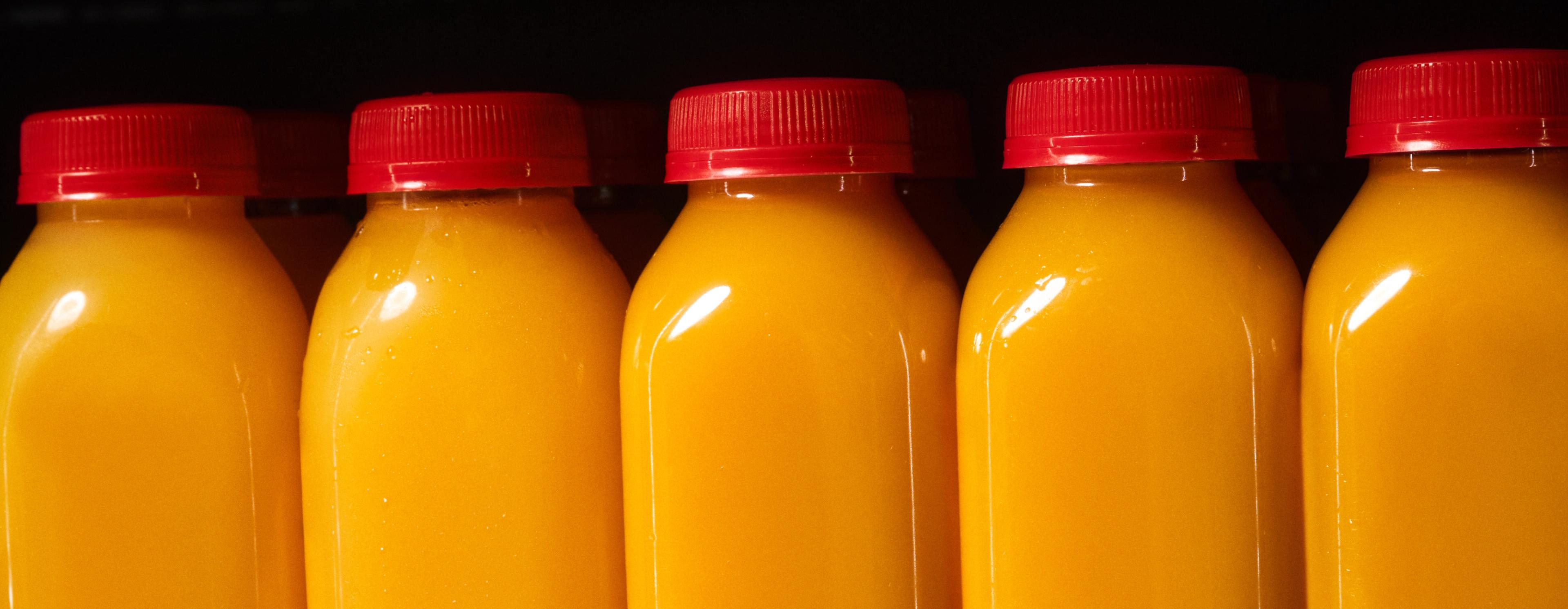 Unlabeled bottles of orange juice with red caps