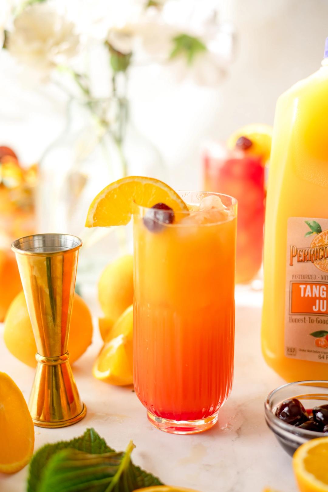 Tangerine Tequila Sunrise made with Perricone Farms Tangerine Juice and grenadine, served over crushed ice with orange slice and cherry garnish