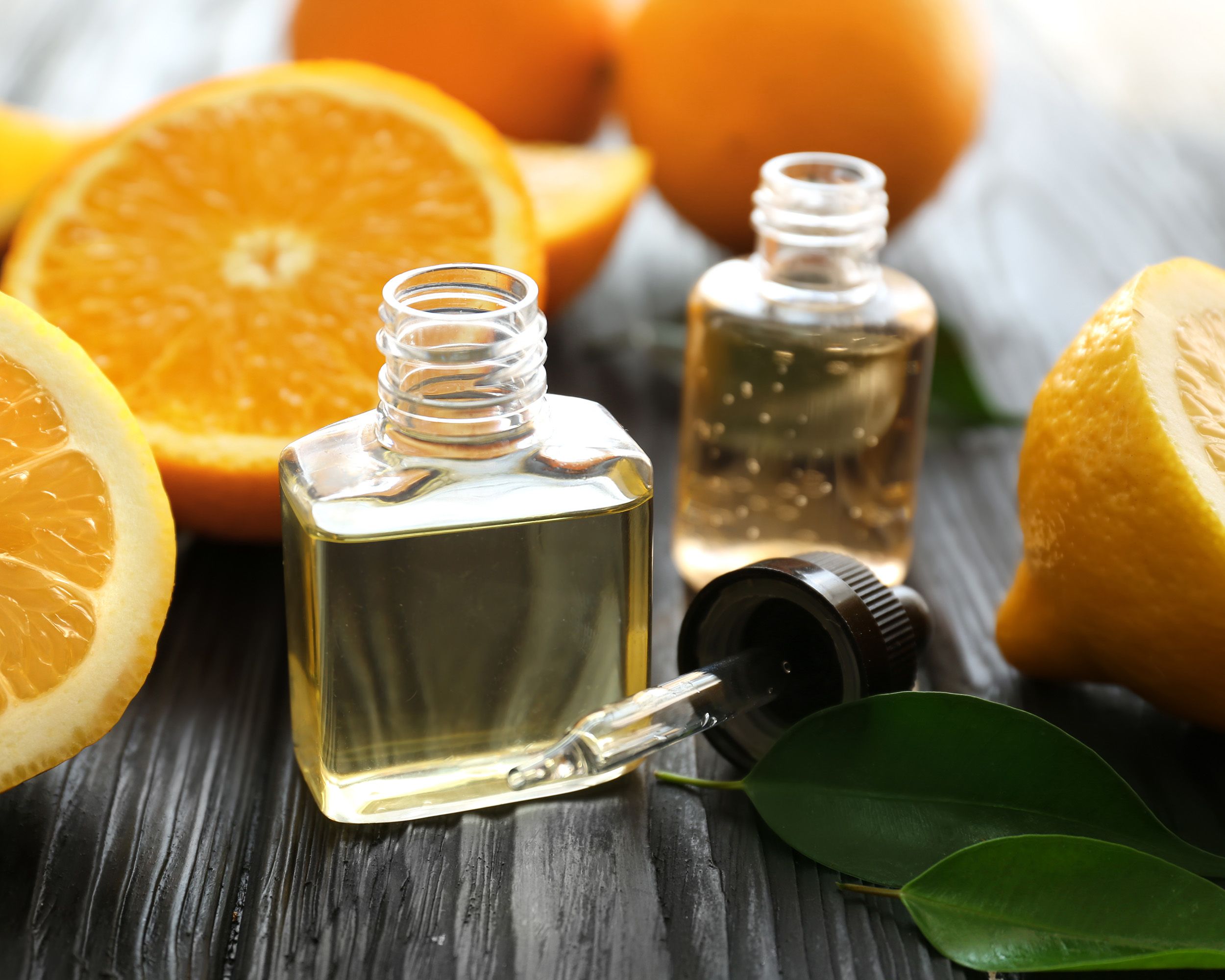 Bottles of citrus oil surrounded by oranges and lemons