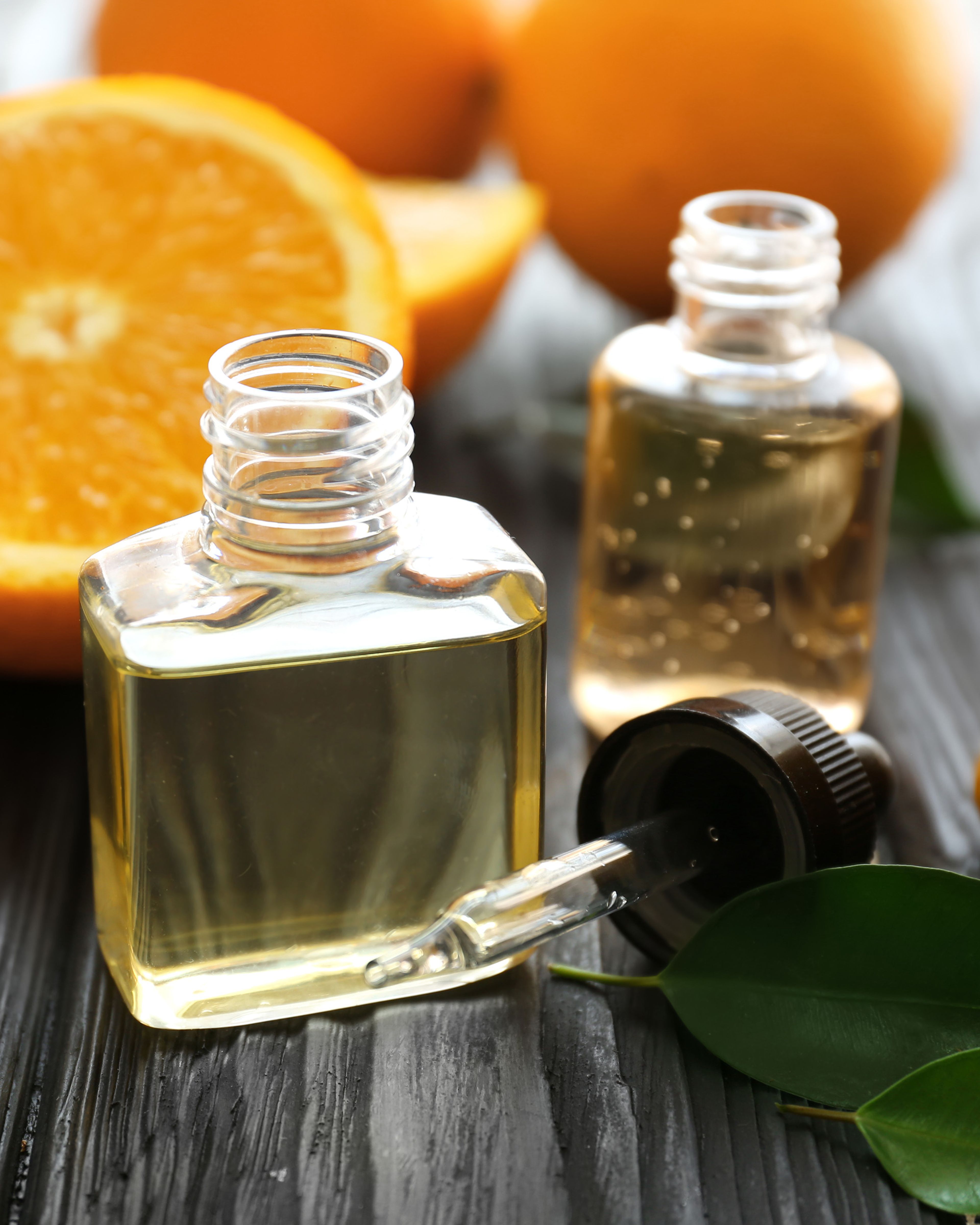 Bottles of citrus oil surrounded by oranges and lemons