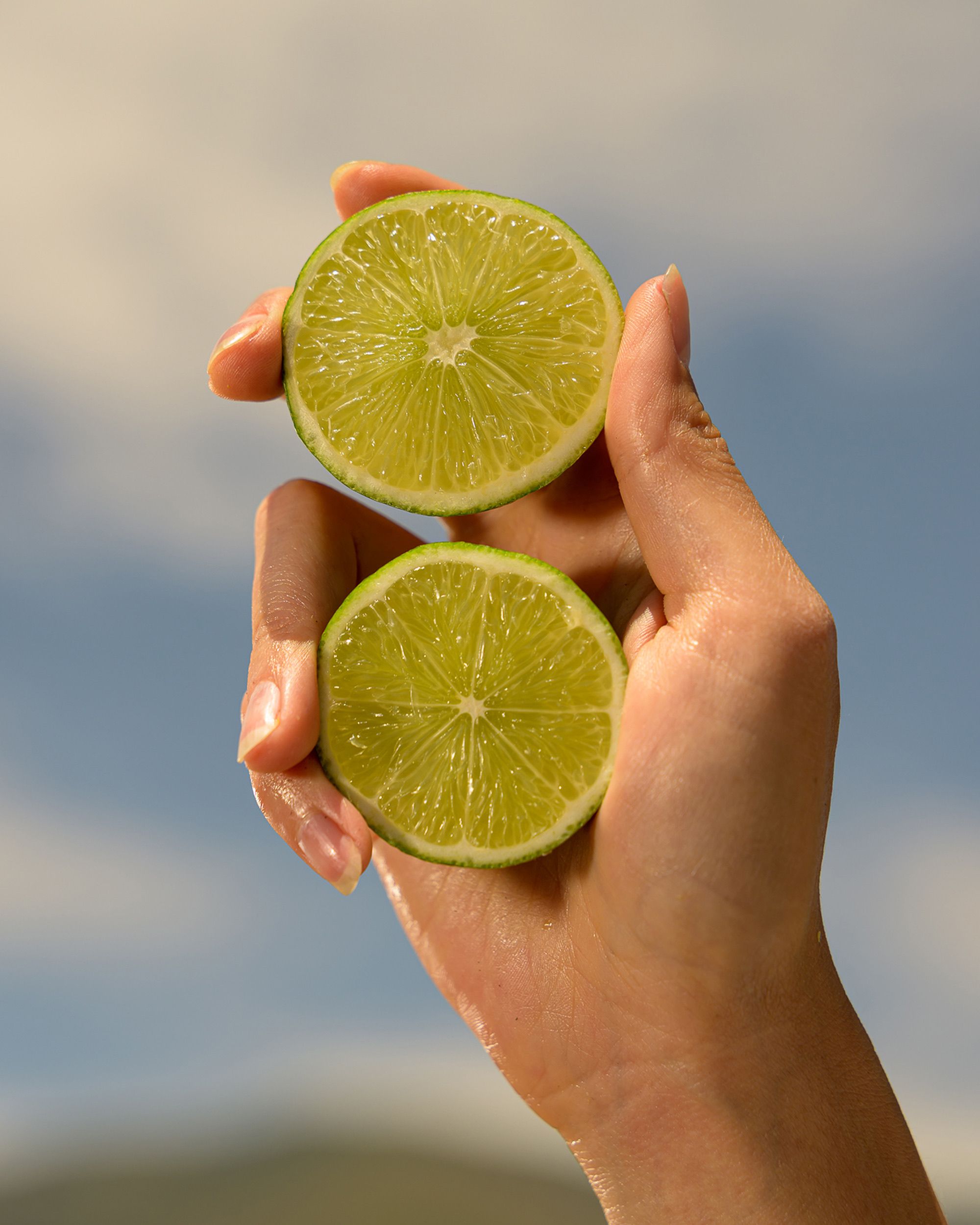Lime slices held against a blue sky