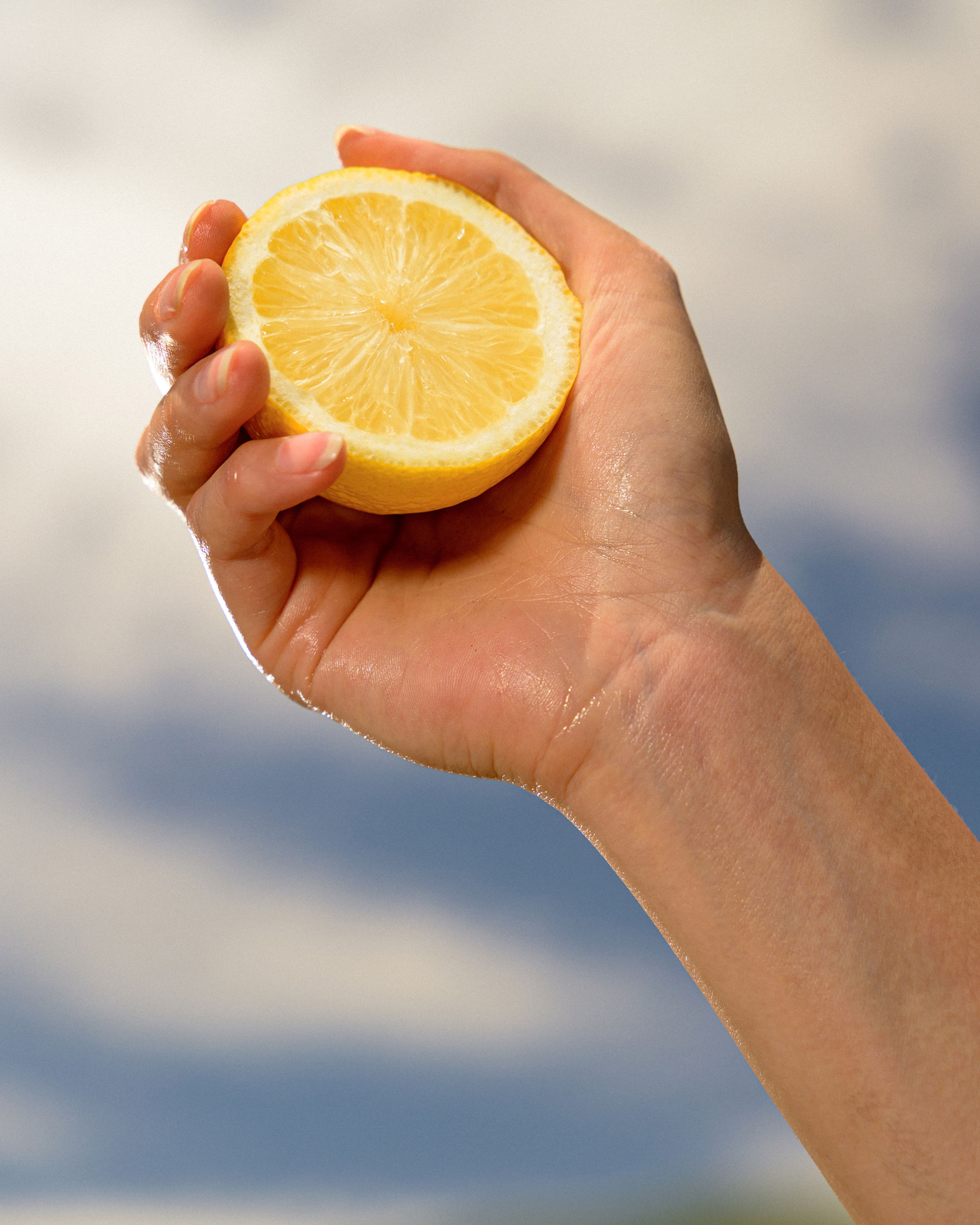 A worker holds a lemon half against the sky