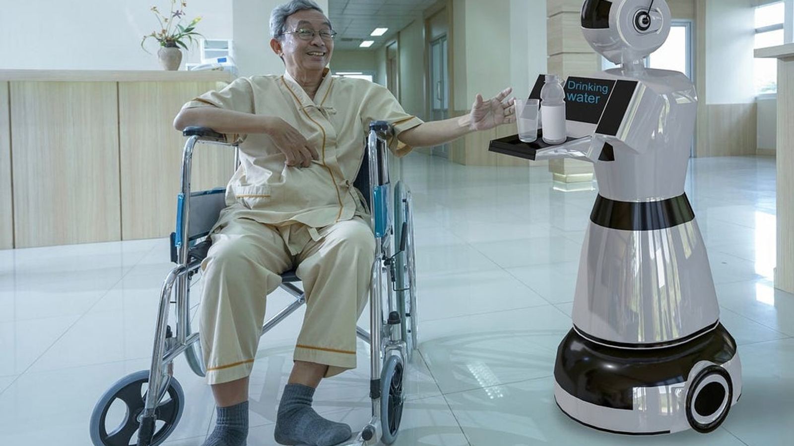 Ein weisser Service-Roboter bringt einem lächelnden älteren Mann im Rollstuhl ein Tablett mit Trinkwasser in einem hellen, modernen Pflegeflur.