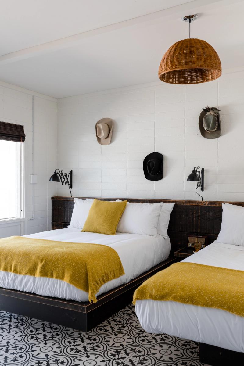 Two-bed room with cowboy hats mounted above the headboards and a black-and-white patterned floor