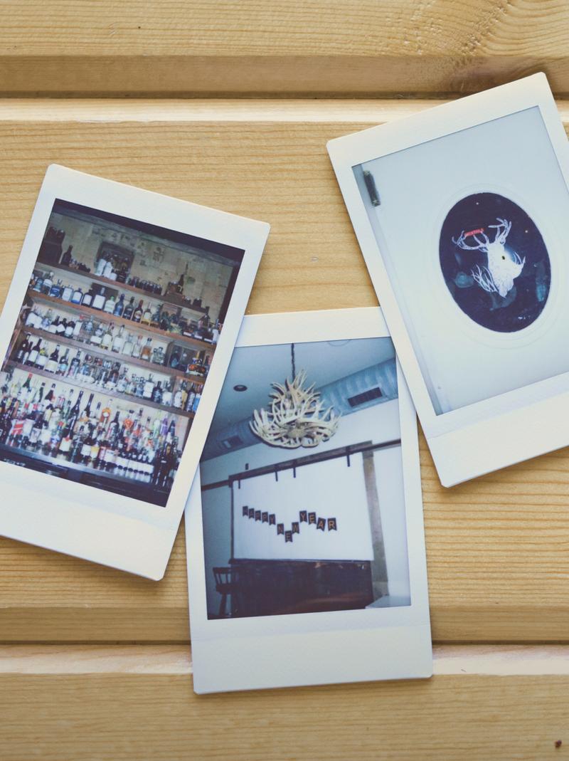 Three Polaroid prints of the hotel laid out on a pale wooden surface.