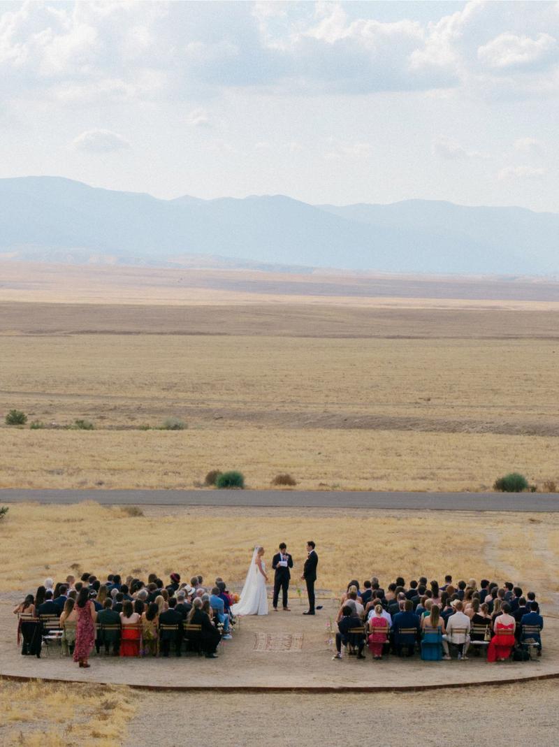 Wedding ceremony set up in the open high-desert valley with mountains behind
