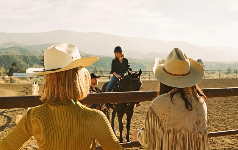 Two women looking out at another woman on a horse