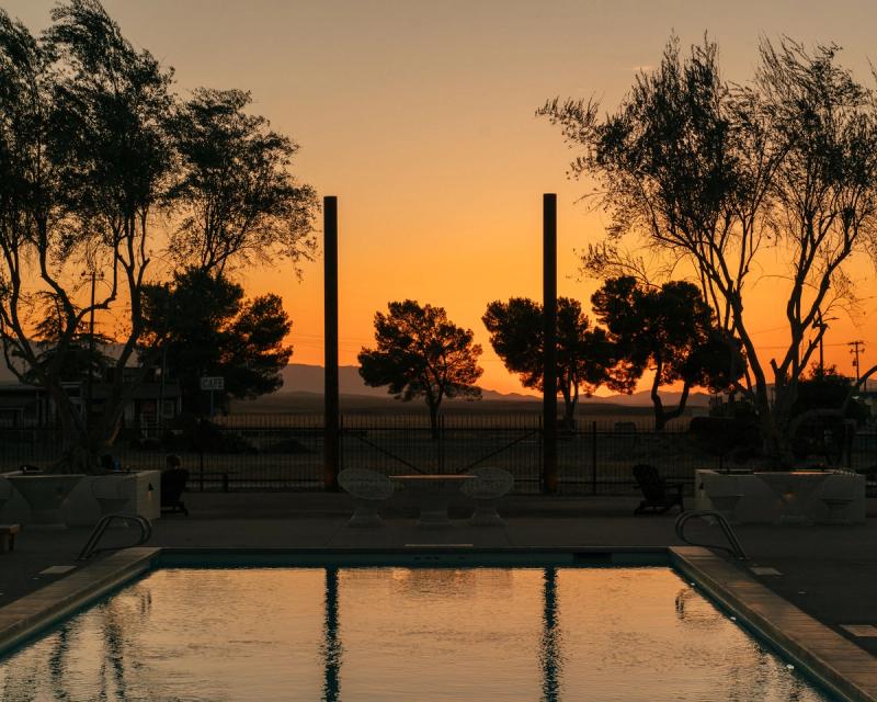 The pool and loungers on The Vista at sunset, the sky orange behind the trees.