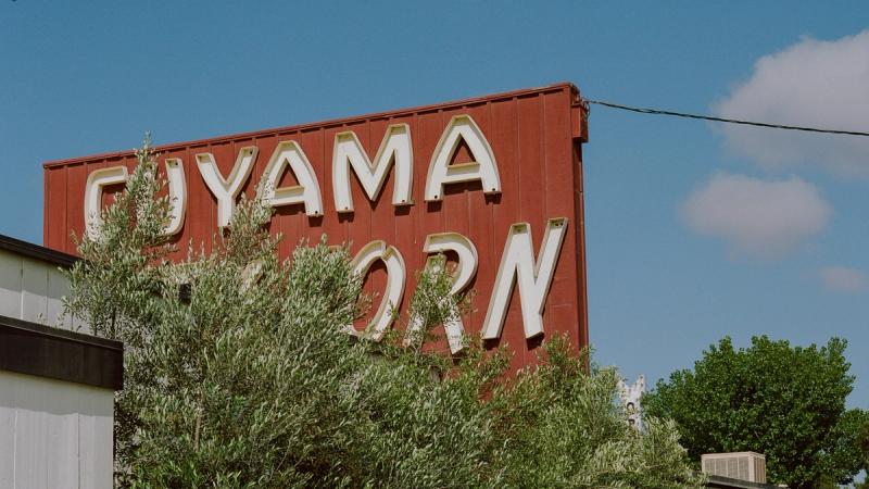 The red Cuyama Buckhorn sign atop the building, framed by trees