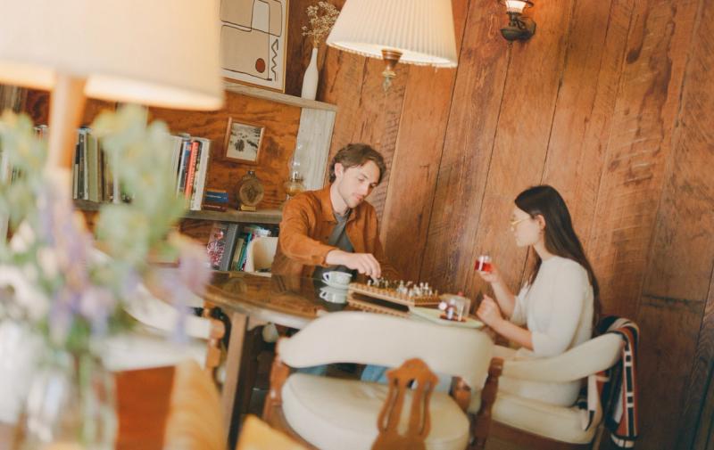 Two guests playing chess in the wood-panelled lobby beneath vintage lamps.