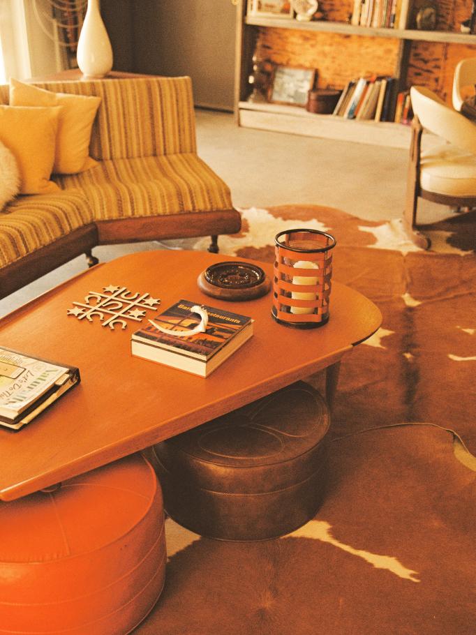 A sunlit lobby lounge with a coffee table, books and a striped sofa