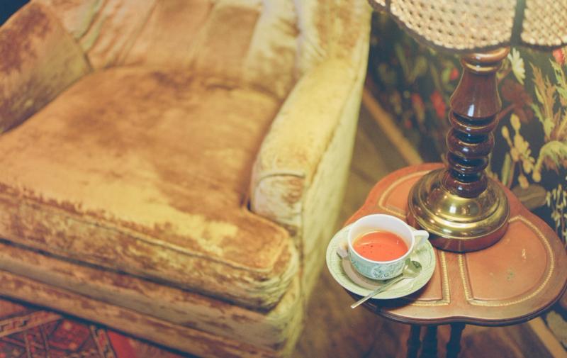 A cup of tea on a small side table beside a velvet sofa in the tea room.