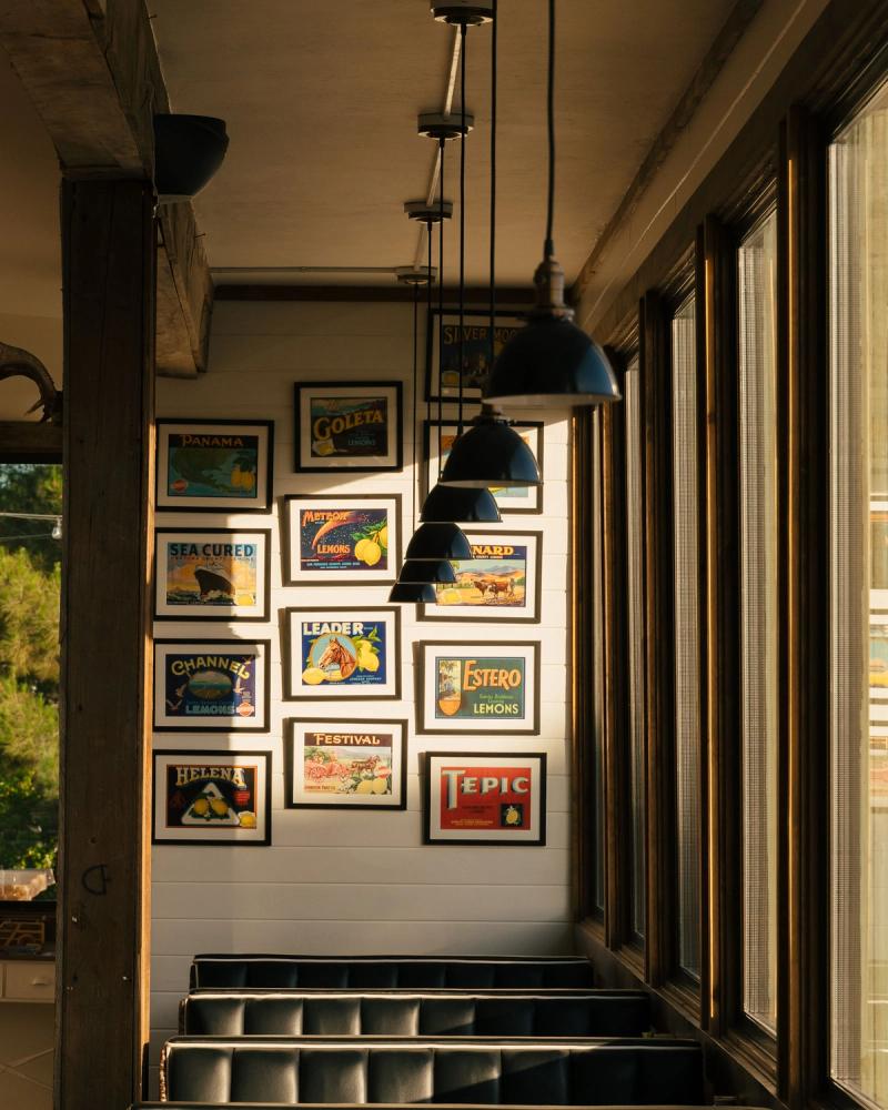 A sunlit dining room hung with vintage produce-crate labels, looking down a row of diner booths.