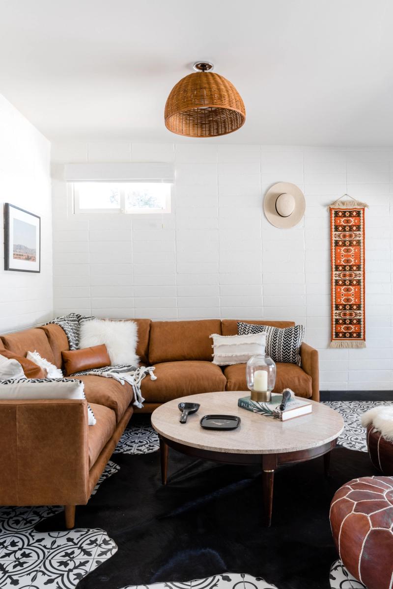 Living area with a tan leather sectional, woven pendant light and a patterned rug