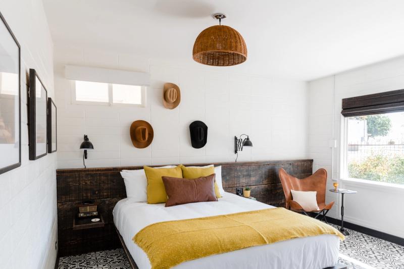 Room with hats displayed on the wall, wood headboard and a leather chair by the window