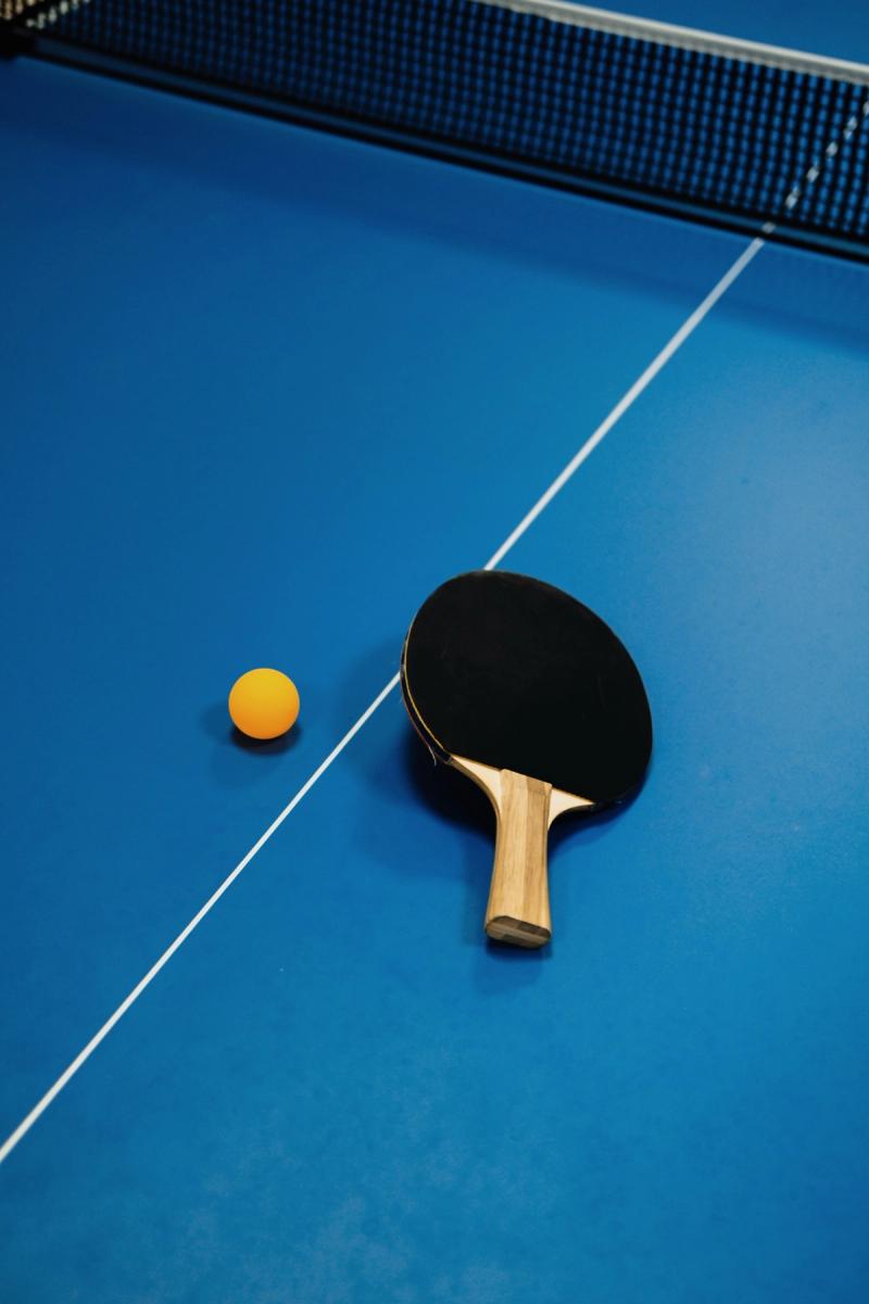 Table tennis paddle and ball resting on a blue table