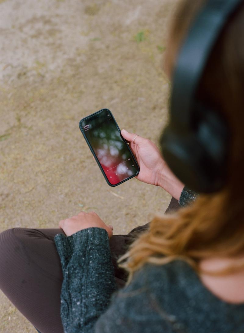 A guest in headphones queueing up a guided meditation on their phone.
