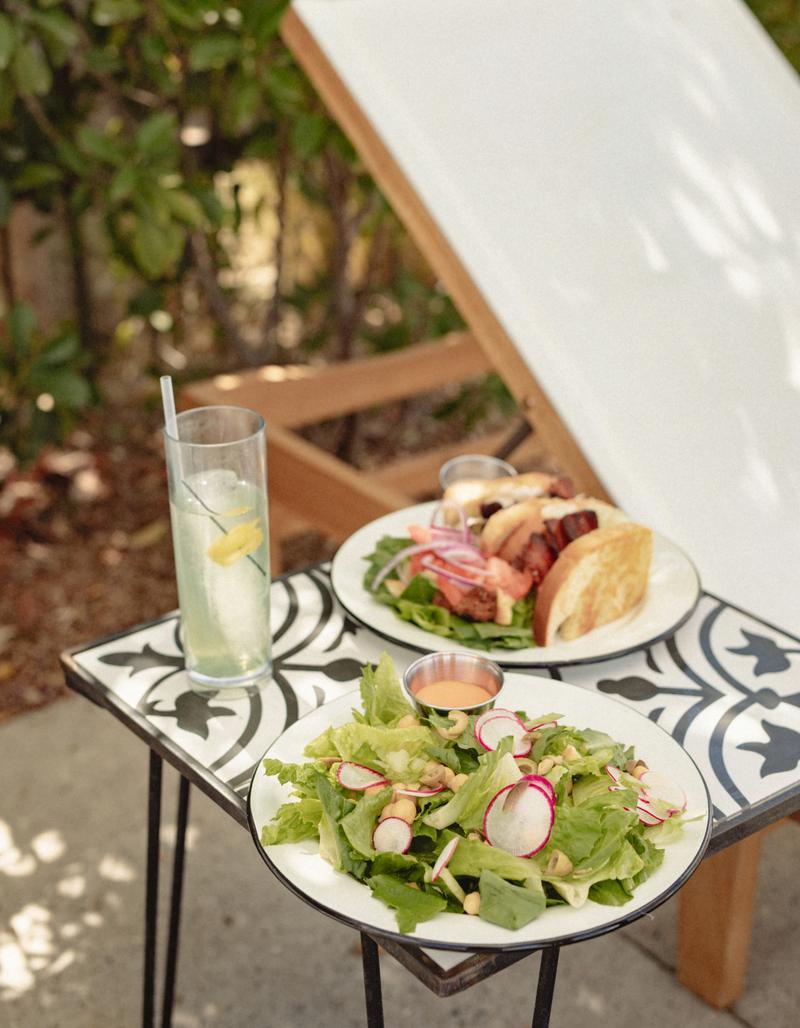 A poolside lunch and drink served on a tiled side table