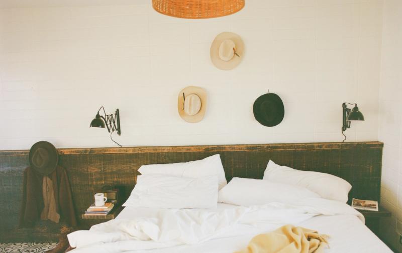 Cowboy hats hung above a bed with reading lamps and a yellow throw blanket