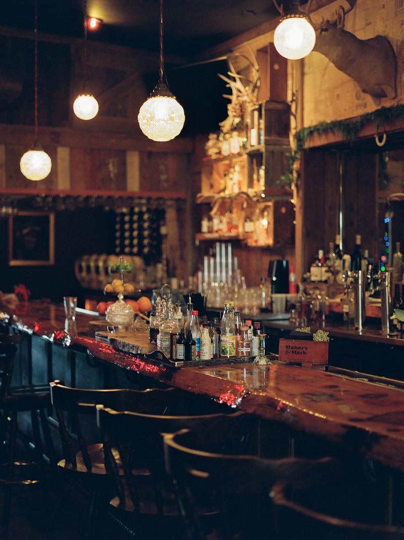 A softly lit bar with. a row of chairs and an array of bottles on the counter