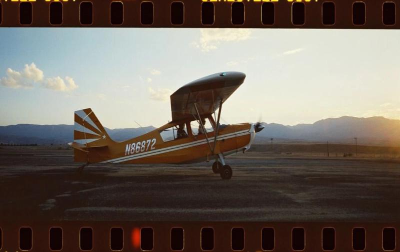 A yellow biplane parked on the L88 airstrip at sunset, shot on 35mm film.