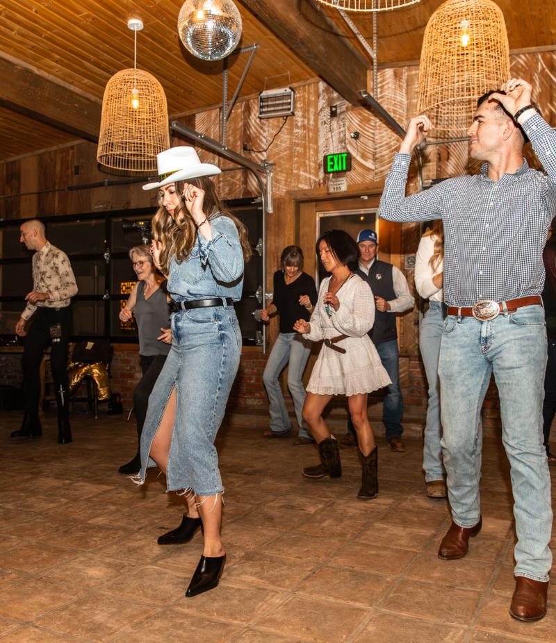 Dancers in cowboy hats line dancing under the Buckhorn's woven pendant lights