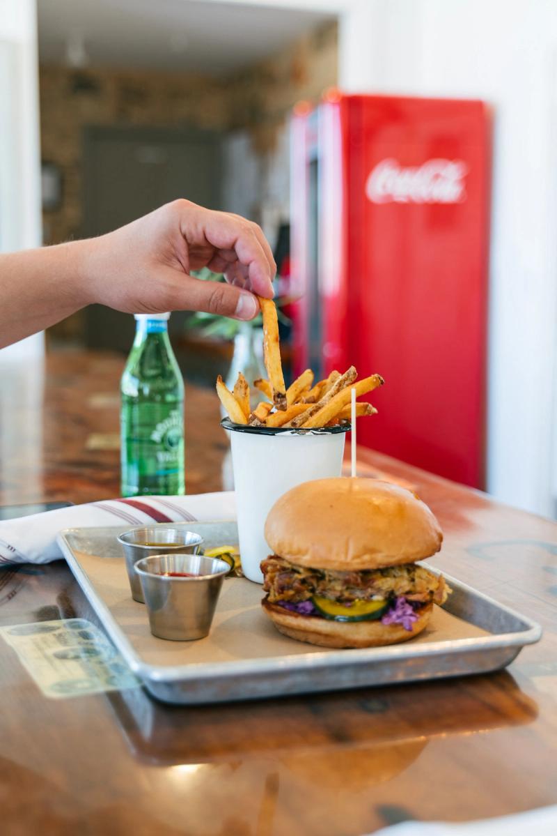 A fried chicken sandwich and fries beside a vintage Coca-Cola cooler