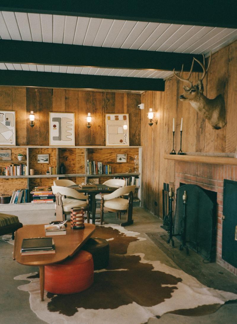 Wood-paneled lounge with a mounted deer head over the fireplace