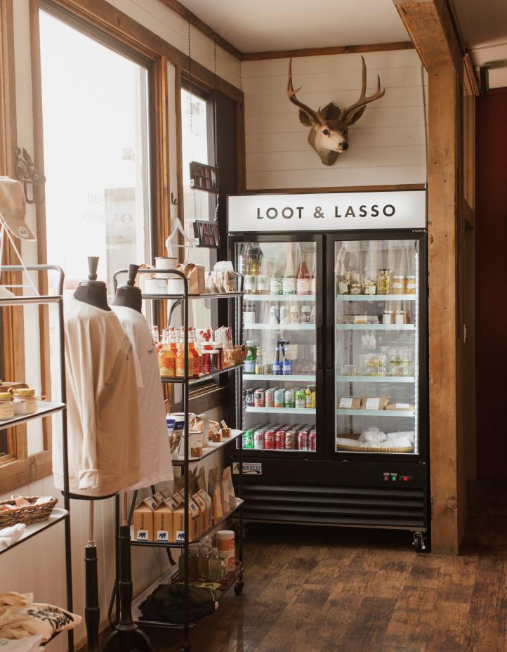 Loot & Lasso market cooler stocked with drinks and snacks below a mounted deer head