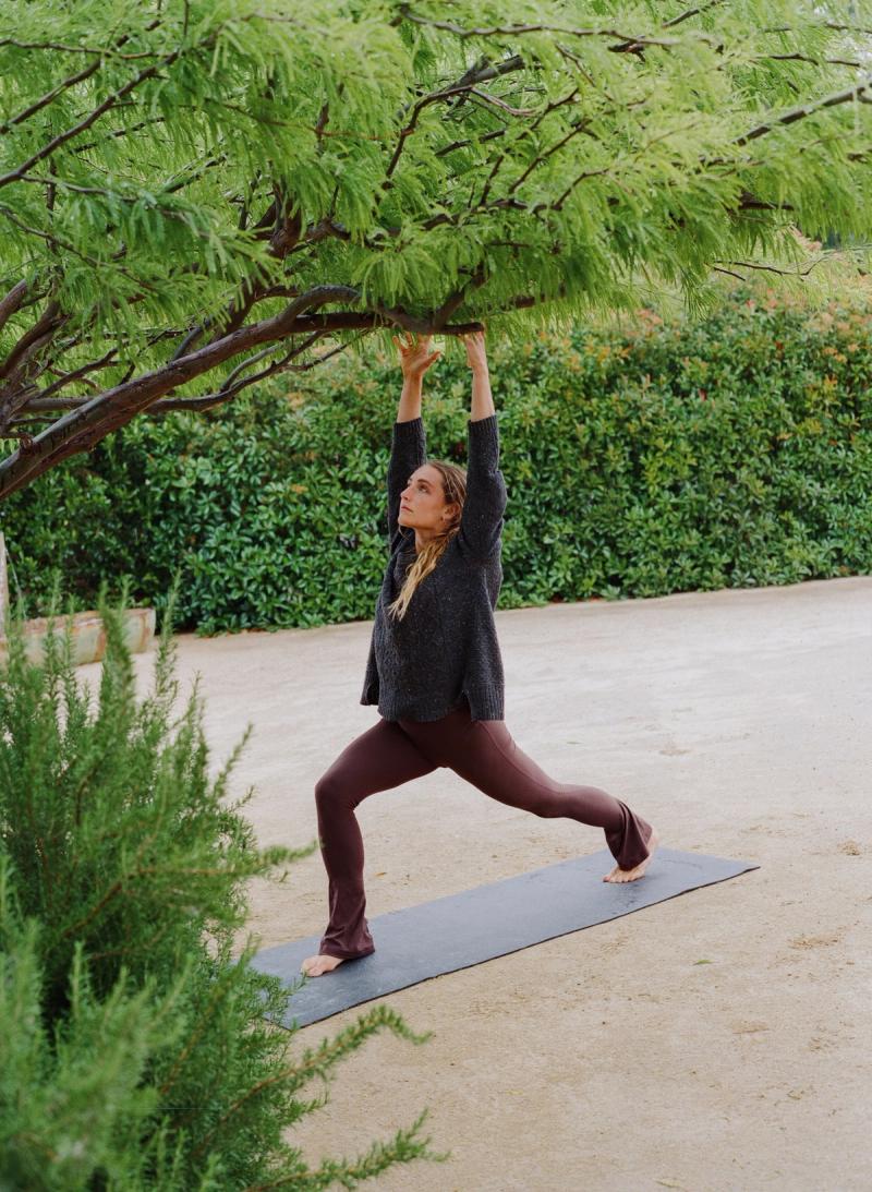 Woman practicing a yoga pose outdoors under a tree