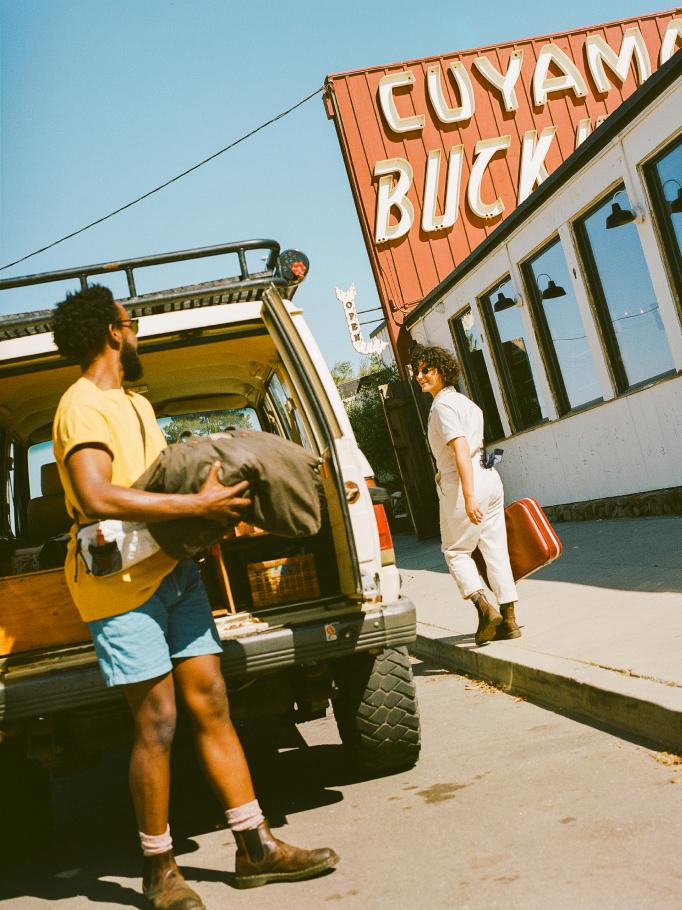 Two guests unloading luggage from a truck outside the Cuyama Buckhorn sign