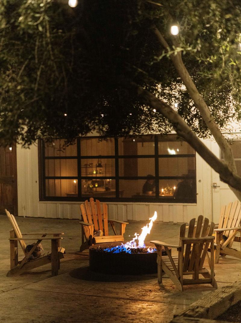 Adirondack chairs around a lit fire pit outside at night