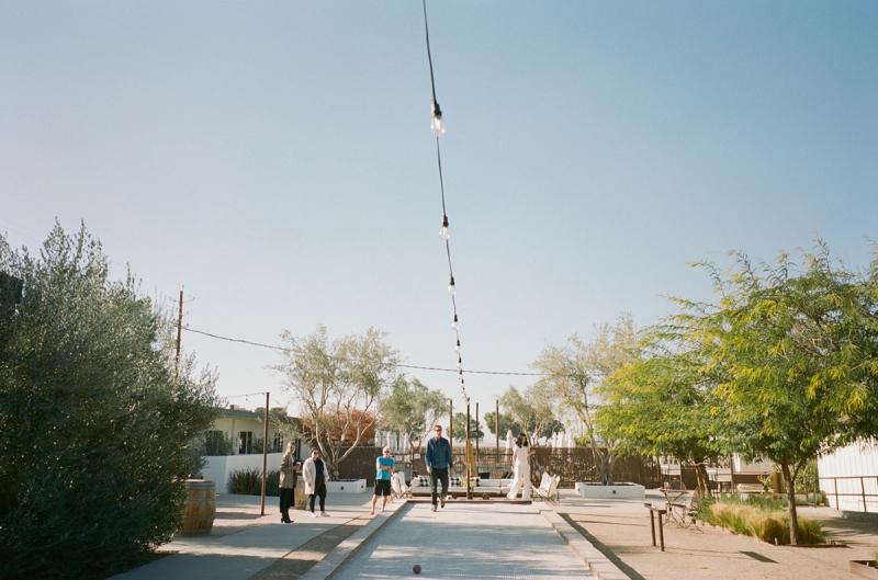 Guests strolling beneath a long string of lights at dusk