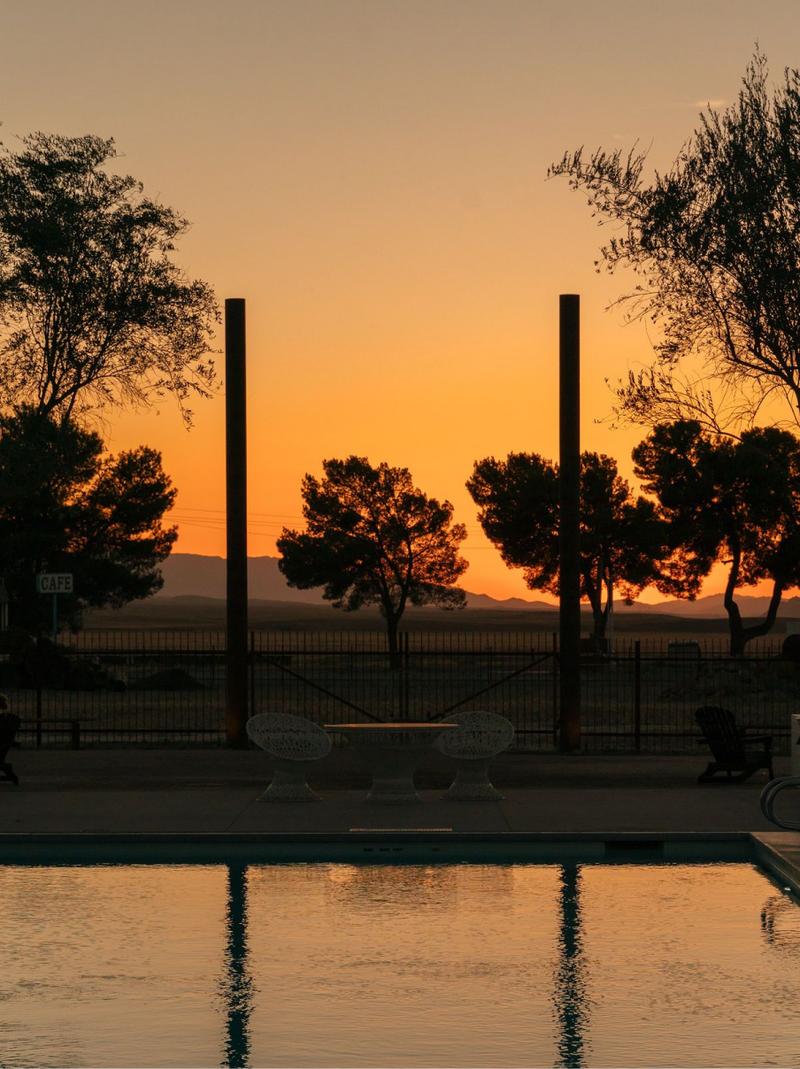 Silhouetted trees and posts reflected in the pool at sunset