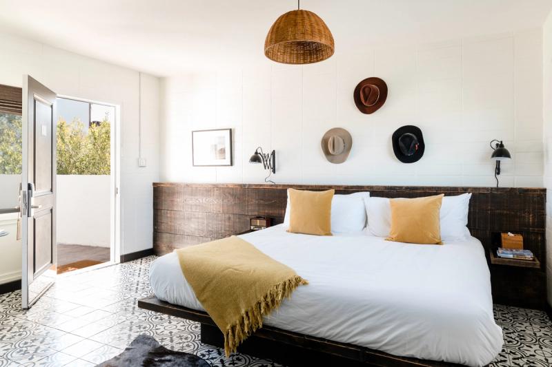 Bedroom with French doors open to a patio, cowboy hats on the wall above the bed