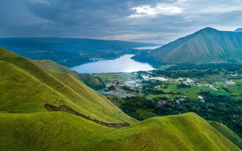 Lake Toba seen from the green hills above the shore, with Batak villages and rice fields below