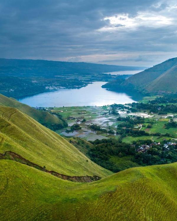 Lake Toba seen from the green hills above the shore, with Batak villages and rice fields below