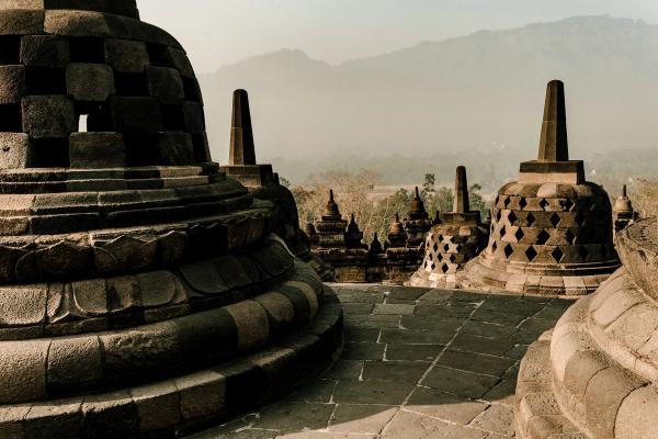Stupas on the upper terrace of Borobudur at sunrise, with haze over the Magelang plain below