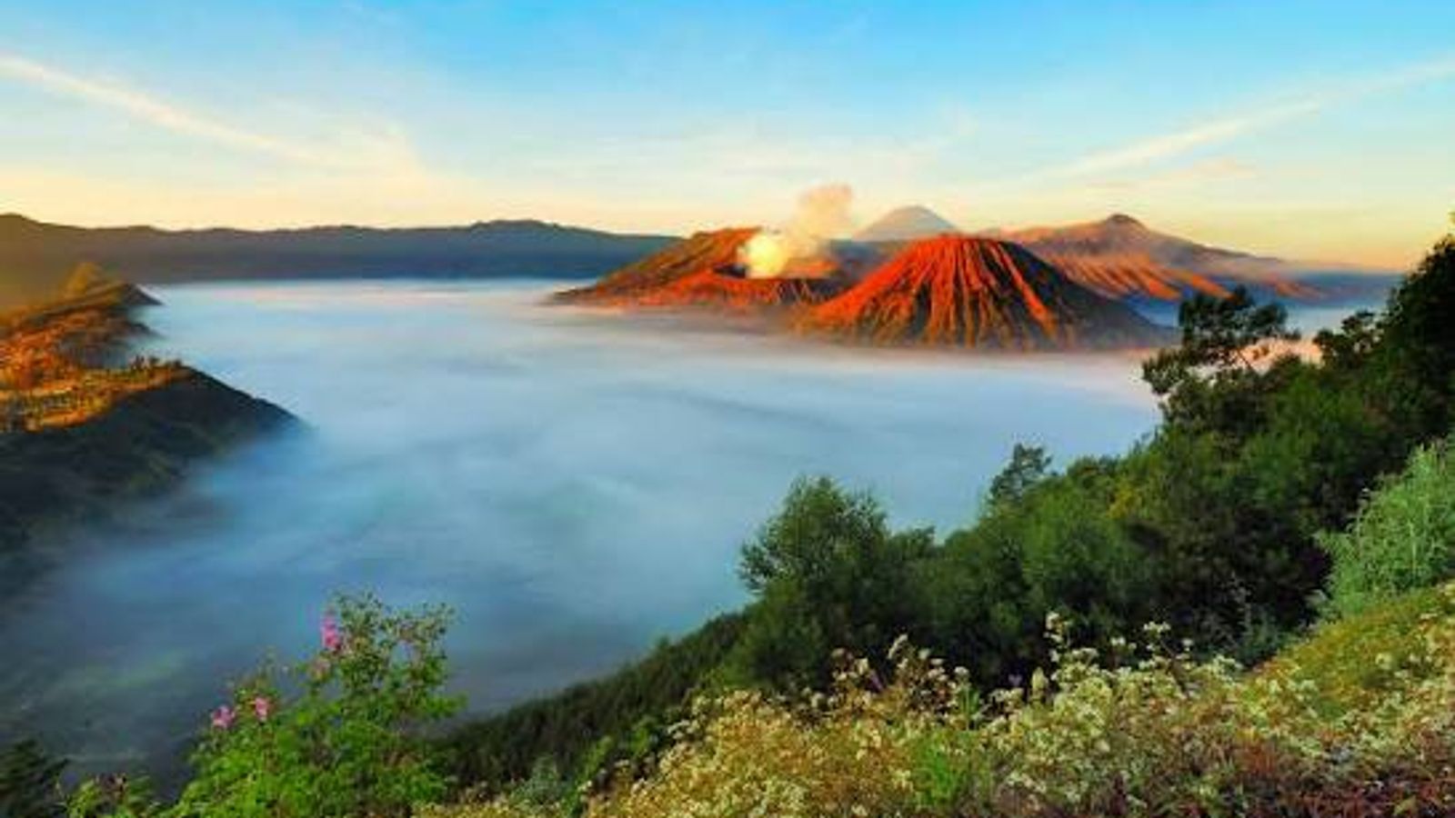Mount Bromo at sunrise, mist filling the Tengger caldera with the crater smoking and Semeru behind