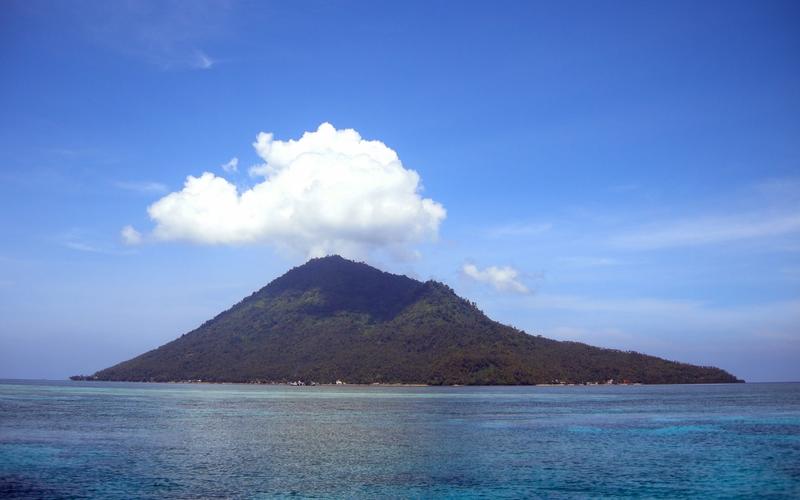 Manado Tua volcano rising above the reef water off Bunaken, North Sulawesi